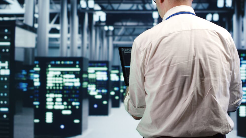 Techniker mit Laptop vor Serverschränken in einem Rechenzentrum